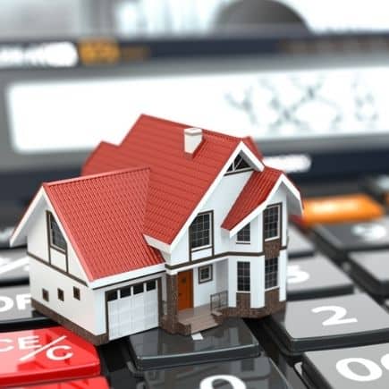 Calculator in background with house sitting on top of it. Why and How we Started Investing in Real Estate featured image.