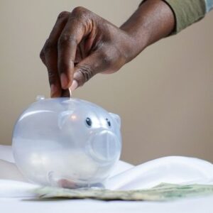 Living Below Your Means - Hand putting change into a piggy bank
