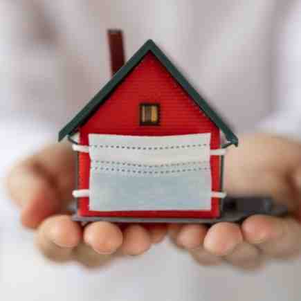 House wearing a mask held in hands - the truth behind real estate investing in the second year of a pandemic.