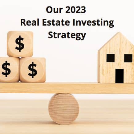 Wooden scale with money blocks on one end and a wooden house on the other. Text title sayind - Our 2023 Real Estate Investing Strategy.